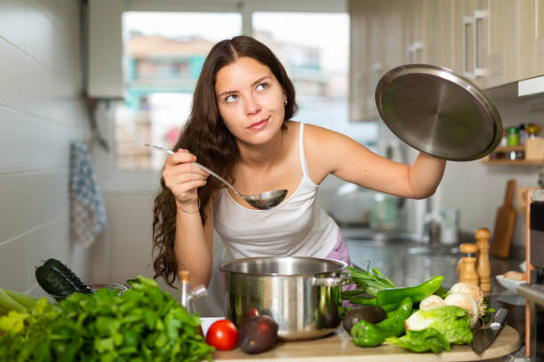 istock Young woman preparing soup in saucepan in kitchen 1493313390