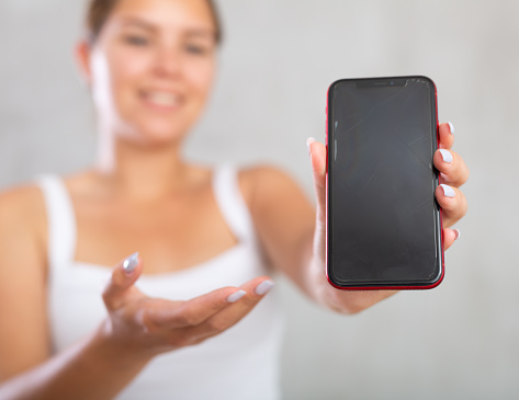 Smiling woman in casual clothes showing the screen of her phone