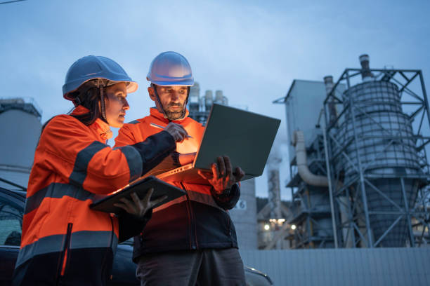 ingenieros trabajando tarde en la planta de energía. trabajo en equipo. - industria petrolera fotografías e imágenes de stock