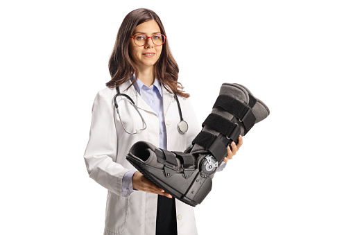 Female doctor holding an orthopedic foot brace isolated on white background