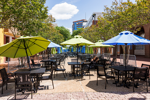 Caucasian woman on weekend activity and city break in side walk cafe with colorful umbrellas. Downtown of Hampton, Virginia