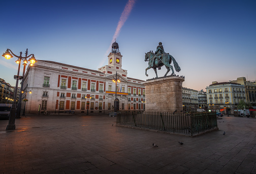Puerta del Sol Square at sunrise with Monument to King Charles III (Carlos III) and Royal House of the Post Office (Real Casa de Correos) - Madrid, Spain