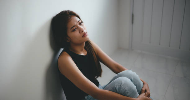 istock Depressed young asian woman sitting on floor 1493350420