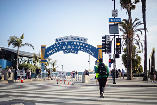 Santa Monica, United States - May 19, 2023. Someone walks on the crosswalk on the orange light, toward Santa Monica Pier.