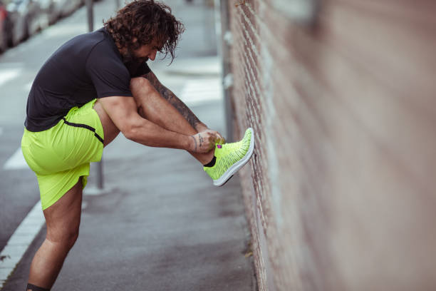 istock Young man tying his shoelaces while out on a jog in the city 1493355928