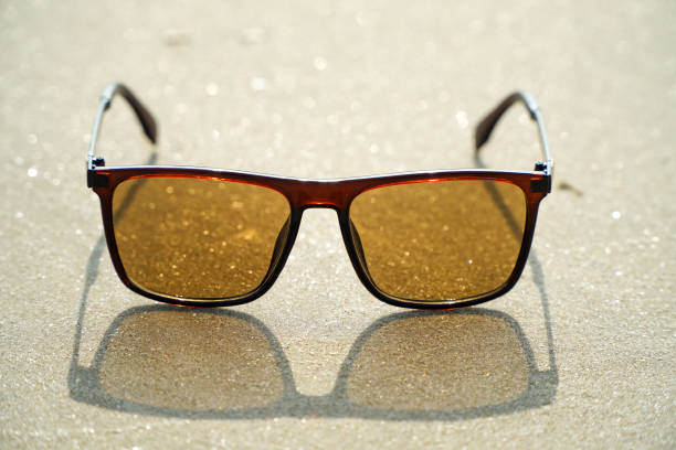 istock Sunglasses with brown glass on the sand. 1493361302
