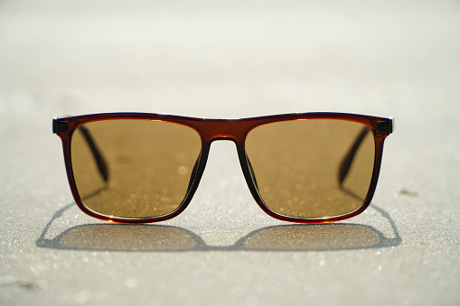 Sunglasses with brown glass on the sand.
