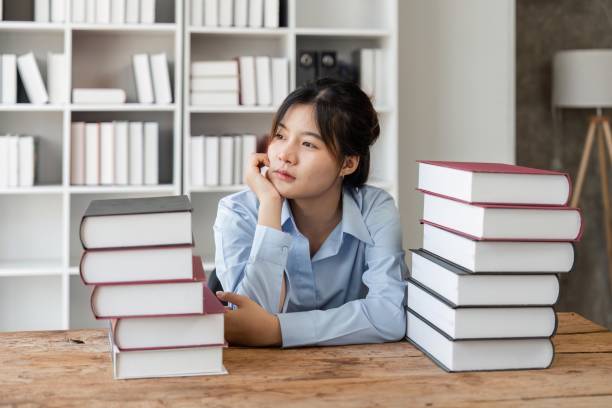 istock Young student girl sit at table with textbooks staring aside, looks pensive and thoughtful search solution, prepare for exam, makes task feels confused or puzzled 1493364582