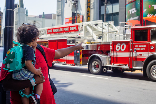 Hollywood, U.S.A. - May 18, 2023. A father and son look at a firetruck as it drives down Hollywood Boulevard.