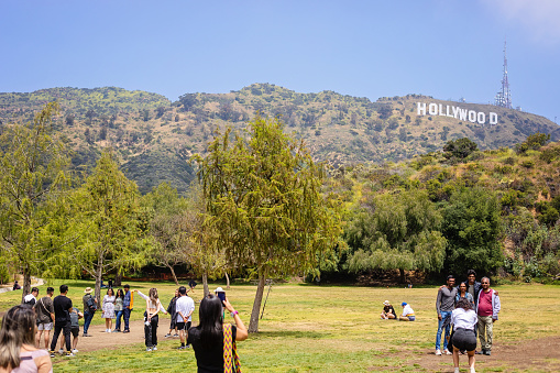 Hollywood, U.S.A. - May 18, 2023. People gather to take their photo with the Hollywood sign as viewed in Lake Hollywood Park.