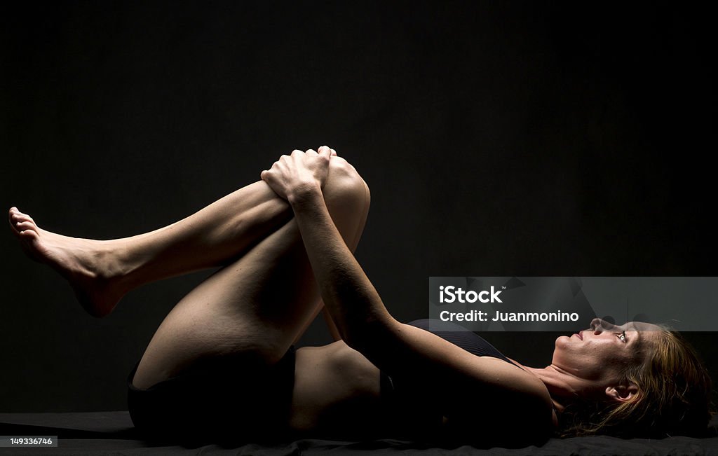 Yoga class Caucasian woman practicing yoga on black background Lying Down Stock Photo