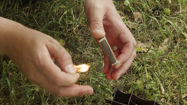 A man lights a match for a fire.