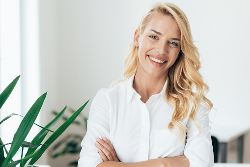 Portrait of beautiful Businesswoman with arms crossed at the odfice. Confident female professional looking at camera and smiling.