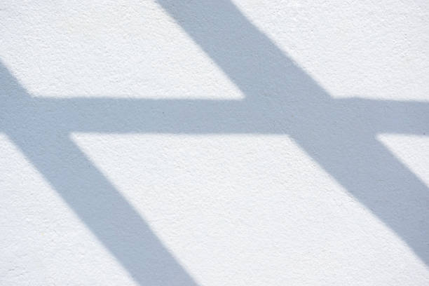 Abstract background of cross shadows on a white wall.
