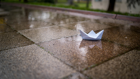 Paper boat floating on water in autumn park