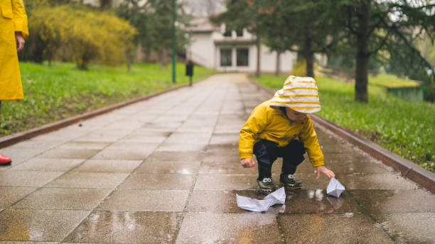 istock Child playing with paper boats in water puddle 1493382147