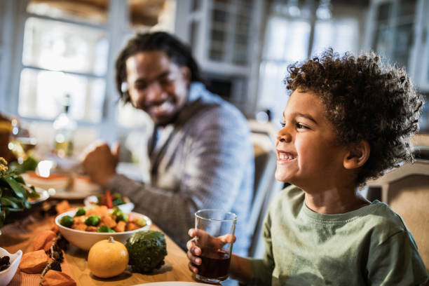 istock Happy black boy having a meal with his father at dining table. 1493385625