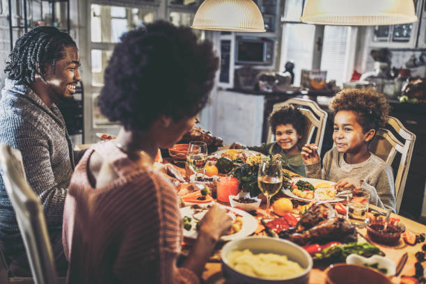 istock Happy black parents and their kids talking during Thanksgiving dinner at home. 1493386250
