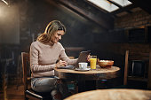 Smiling woman using a computer in a café.
