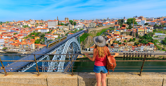 Woman tourist lookgin at panoramic cityscape of Porto- Portugal with famous Luiz Bridge and Douro river
