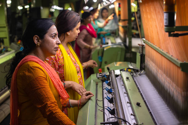 istock Female workers operating manufacturing equipment at textile factory 1493391197