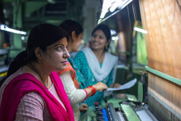 istock Female workers operating manufacturing equipment at textile factory 1493391253