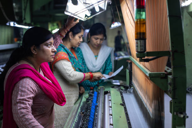 istock Female workers operating manufacturing equipment at textile factory 1493391371