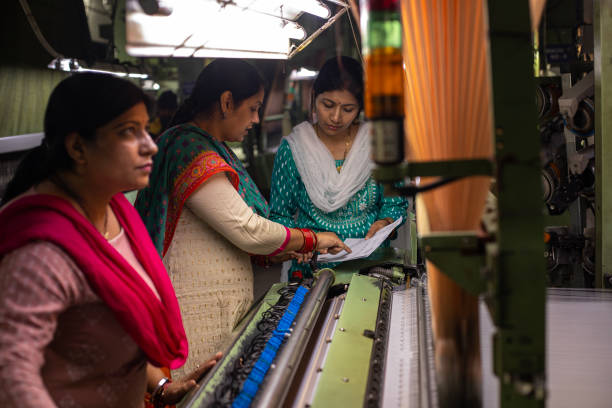 istock Female workers operating manufacturing equipment at textile factory 1493391407