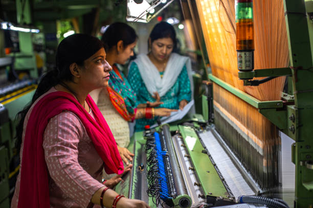 istock Female workers operating manufacturing equipment at textile factory 1493391420