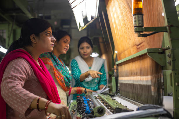 istock Female workers operating manufacturing equipment at textile factory 1493391447