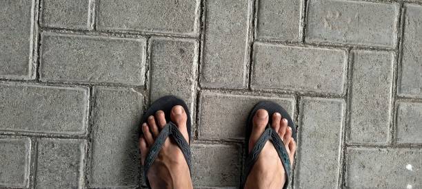 istock Feet wearing black flip flops on a paving block 1493391491