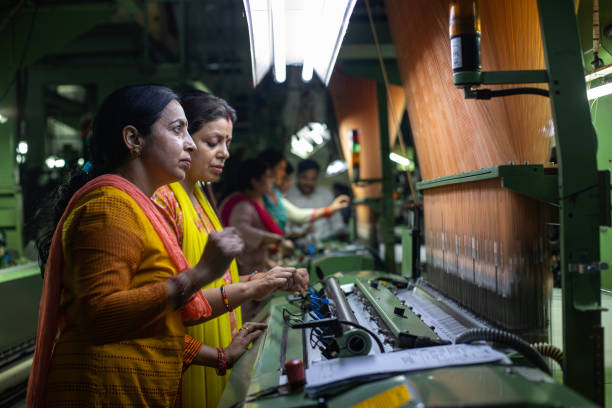 istock Female workers operating manufacturing equipment at textile factory 1493391621