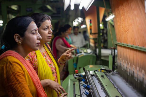 istock Female workers operating manufacturing equipment at textile factory 1493391725