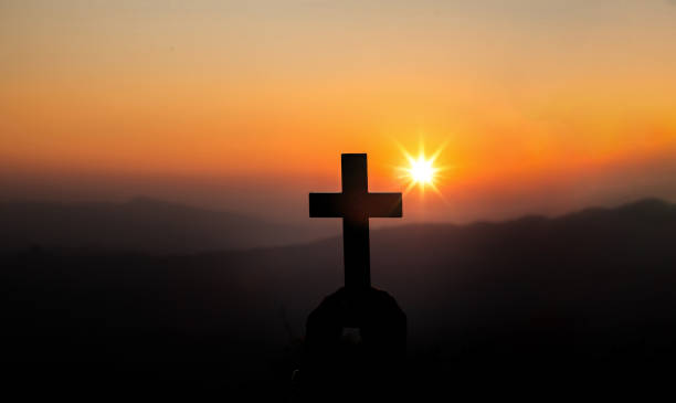 istock Christian holding cross with light sunset background. christian silhouette concept. 1493393584