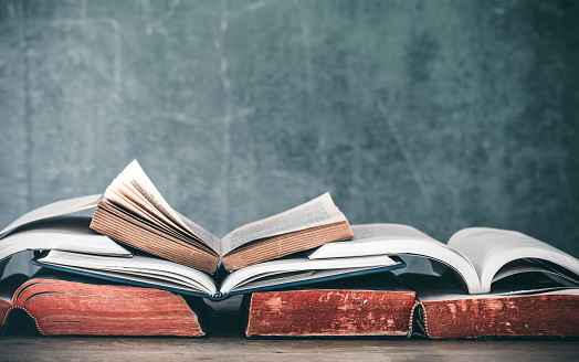 book stack on wooden desk with green chalkboard background. education concept