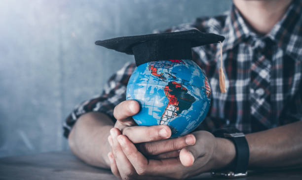 istock Education in global world, graduation cap on globe in young man hands. education concept. 1493393619