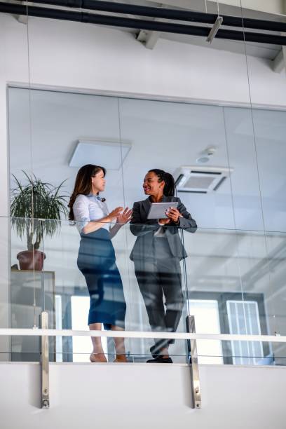 Business people leaning against a glass fence and using a digital tablet
