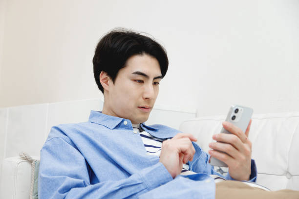 istock Japanese man using a mobile phone in living room 1493398976