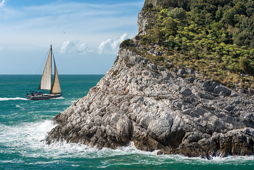 White sailing boat in the Mediterranean sea. Cliff of Palmaria island, Porto Venere or Portovenere, Gulf of La Spezia, Liguria, Italy, Europe.