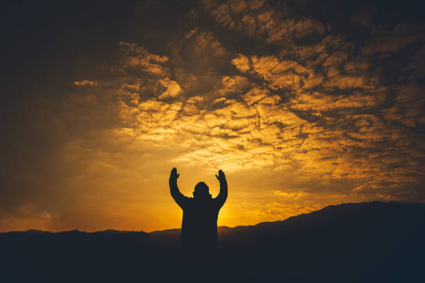istock Man lift hands and Praying at sunset background. christian silhouette concept. 1493401690