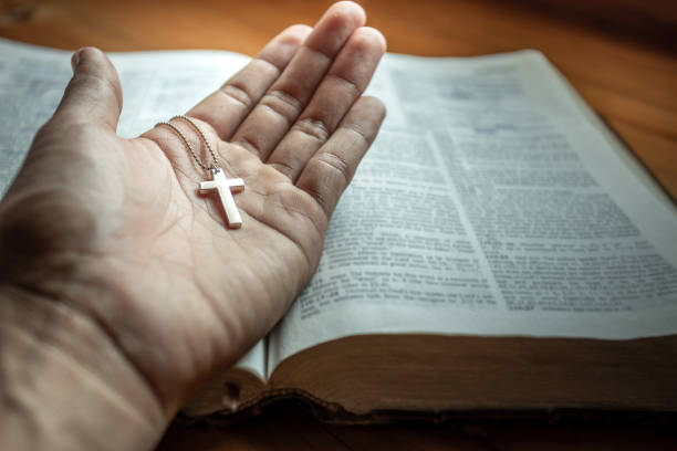 istock Man holding silver jesus cross in hands on bible. religion concept. 1493401743