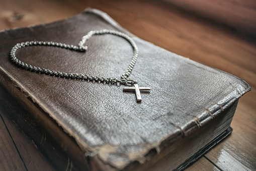 Close up of christian cross necklace on the old holy bible. symbol of christian concept.