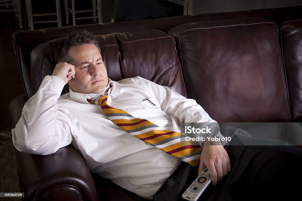 Tired Male watching Television at home A tired businessman watches television at home after a long day Watching TV Stock Photo