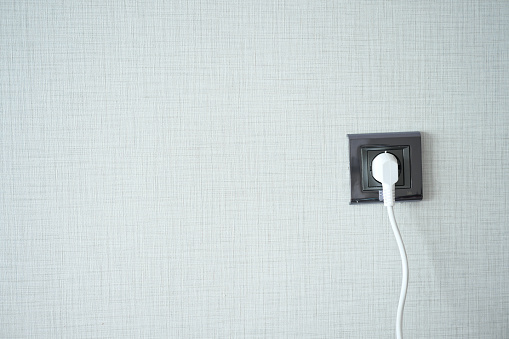 white color power cord cable plugged into wall .