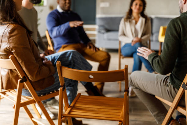 istock Group of people sitting in circle, talking during group therapy 1493413779