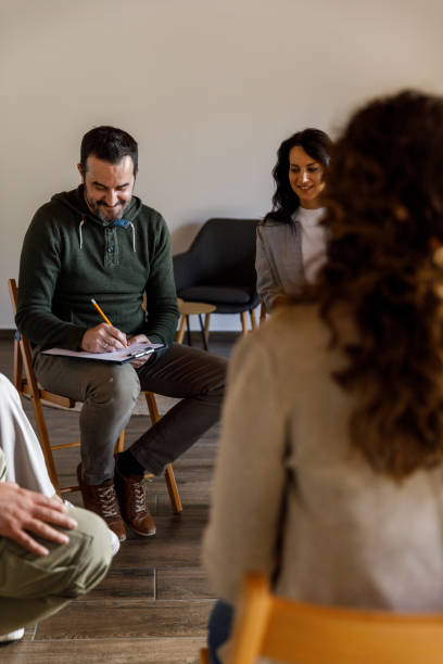 istock Male therapist writing notes on the clipboard during a group therapy session 1493414777