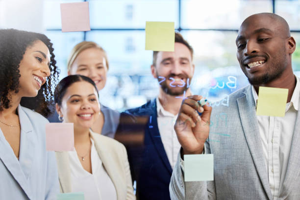 istock Business people, writing and meeting for schedule planning, brainstorming or team collaboration at the office. Group of creative employees in project plan, tasks and post it or sticky note in startup 1493414814