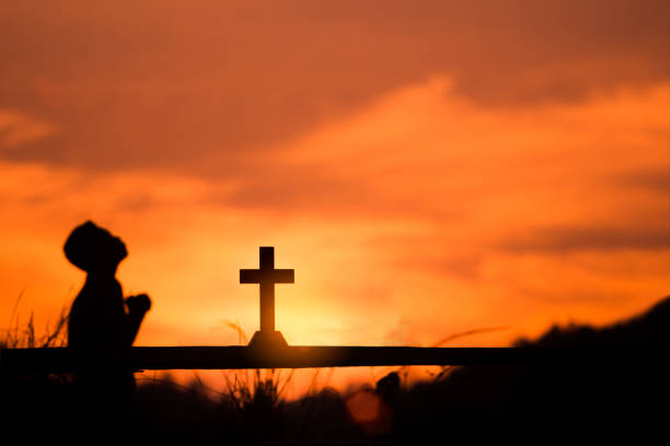 istock Boy praying to God with cross, christian silhouette concept. 1493416331