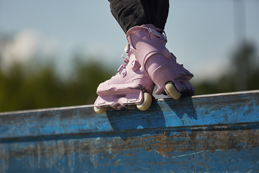 Roller blader female performing a grind trick on a ledge in a outdoor skate park