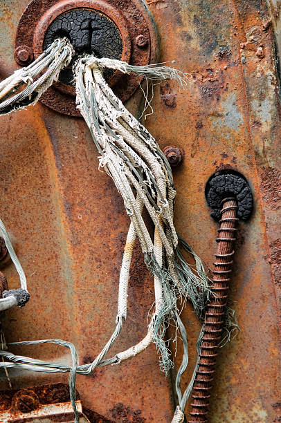 The frayed wires and cables in the engine of an old abandoned car.